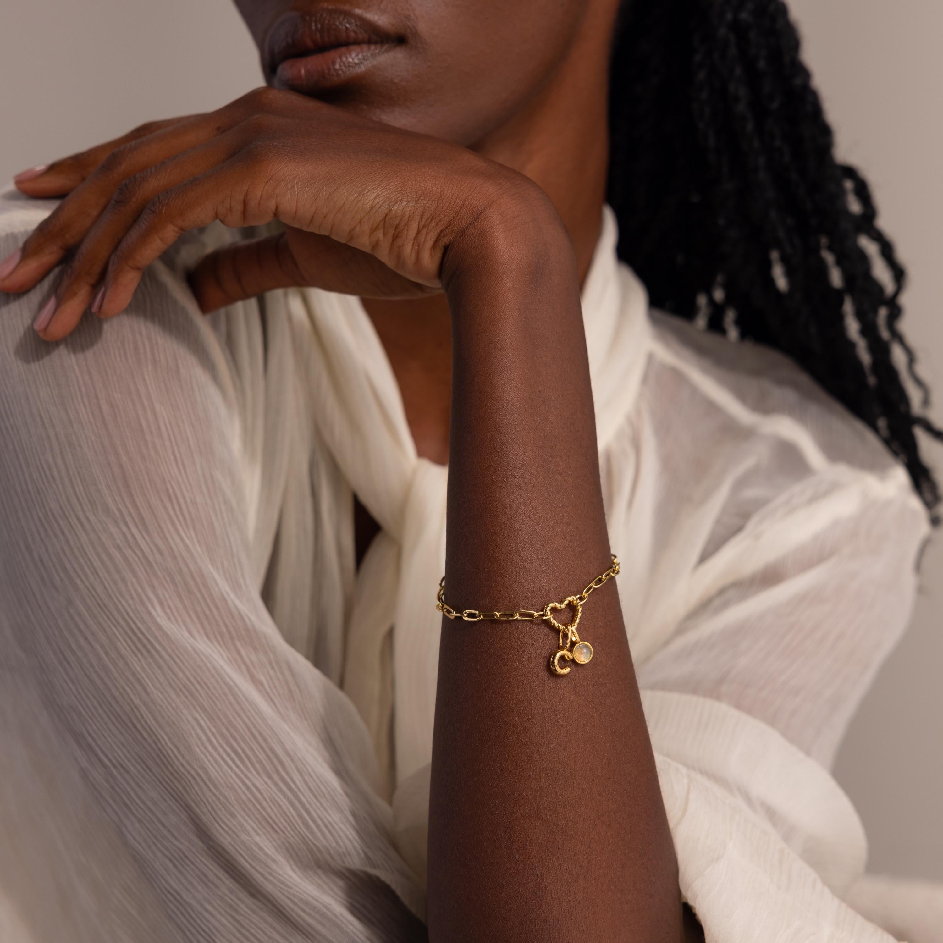 Gold Heart Carabiner Paperclip Bracelet styled with pearl and “C” initial charms on model’s wrist