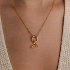 An Aquarius charm dangles from a circular bail on a gold chain, worn as a necklace.