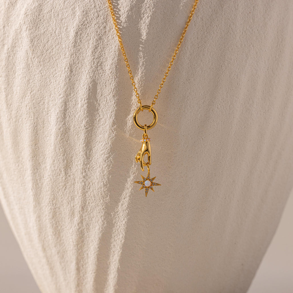 Gold North Star Hand Charm hangs off of a rolo clasp necklace