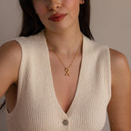 Model wearing a gold necklace with a Heart Hands charm, styled with a cream knit sleeveless top.