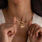 A woman holds the Puff Heart Charm, a gold chain necklace featuring a puff heart and small wing—an affectionate symbol ideal for minimalist jewelry lovers.