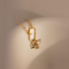 A detailed close-up of a necklace styled with three charms—including the Simple Heart Charm—hanging from a carabiner lock on a curved ceramic form.