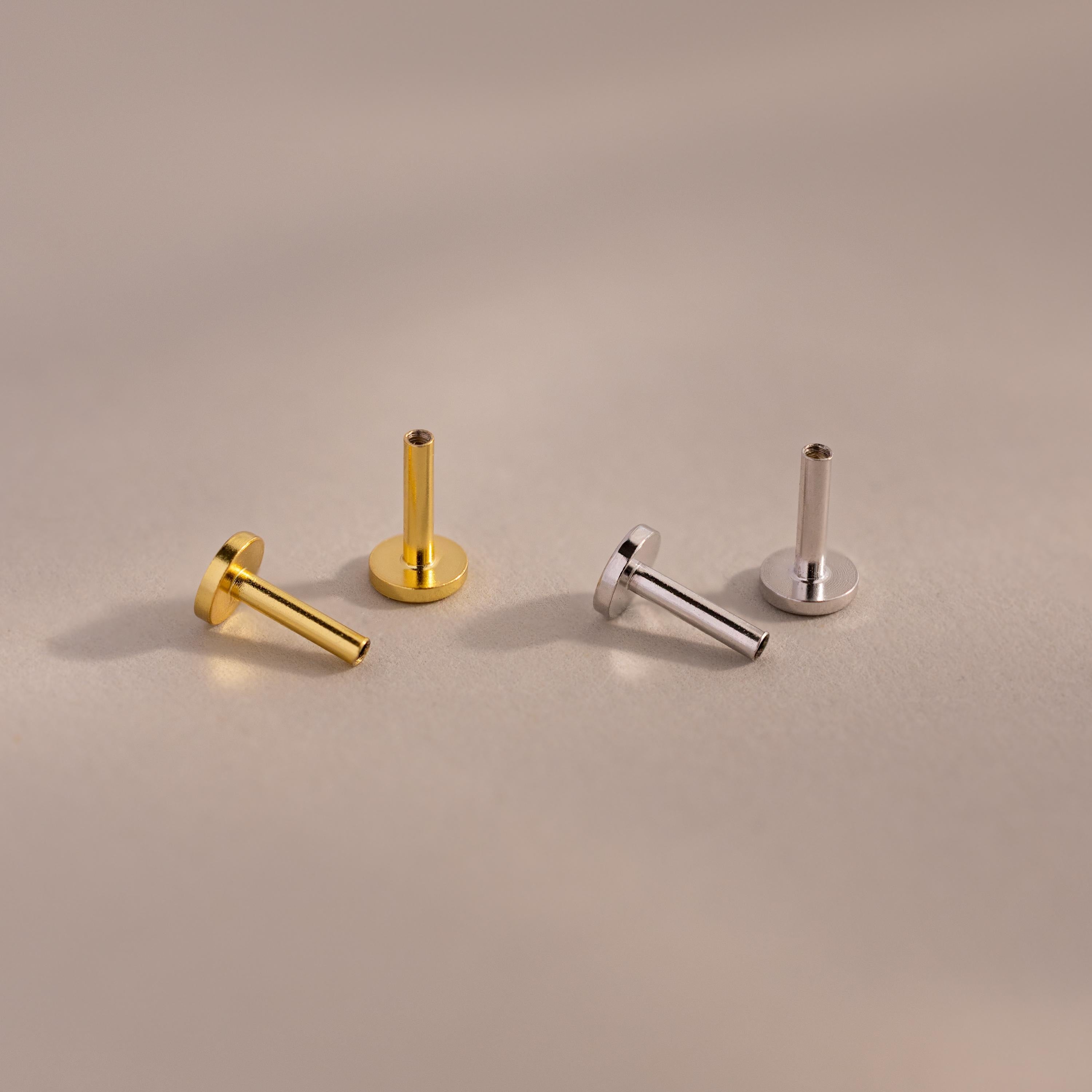 A set of four Flat Back Posts — two gold and two silver — arranged upright and angled on a neutral-toned background.