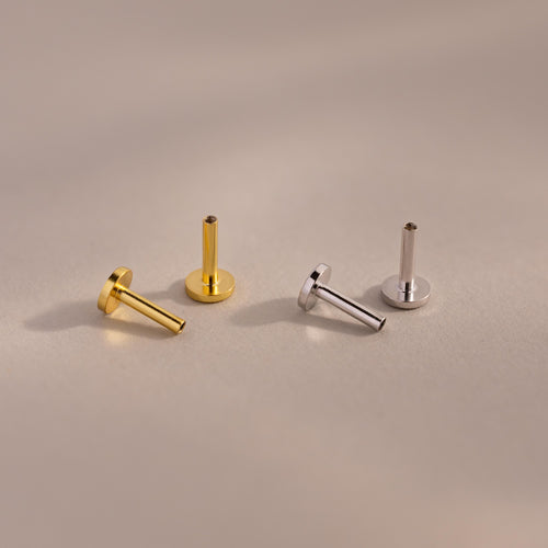 A set of four Flat Back Posts — two gold and two silver — arranged upright and angled on a neutral-toned background.