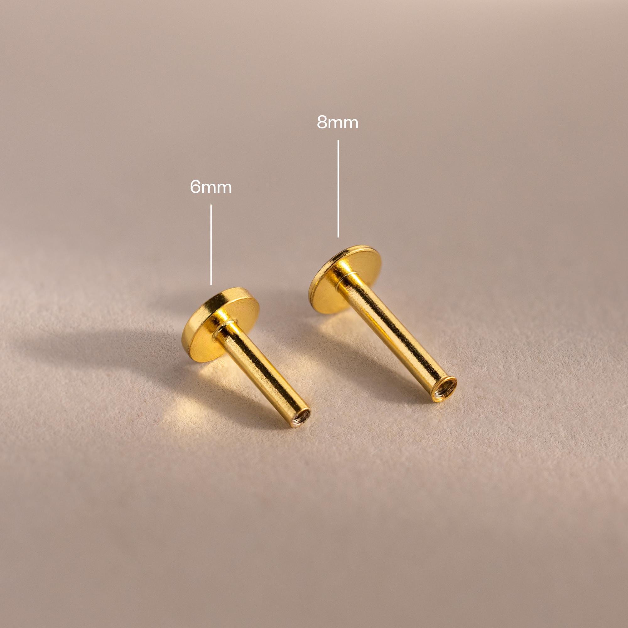 Close-up of two 18k gold Flat Back Posts lying down, showcasing the smooth finish and hollow post detail.