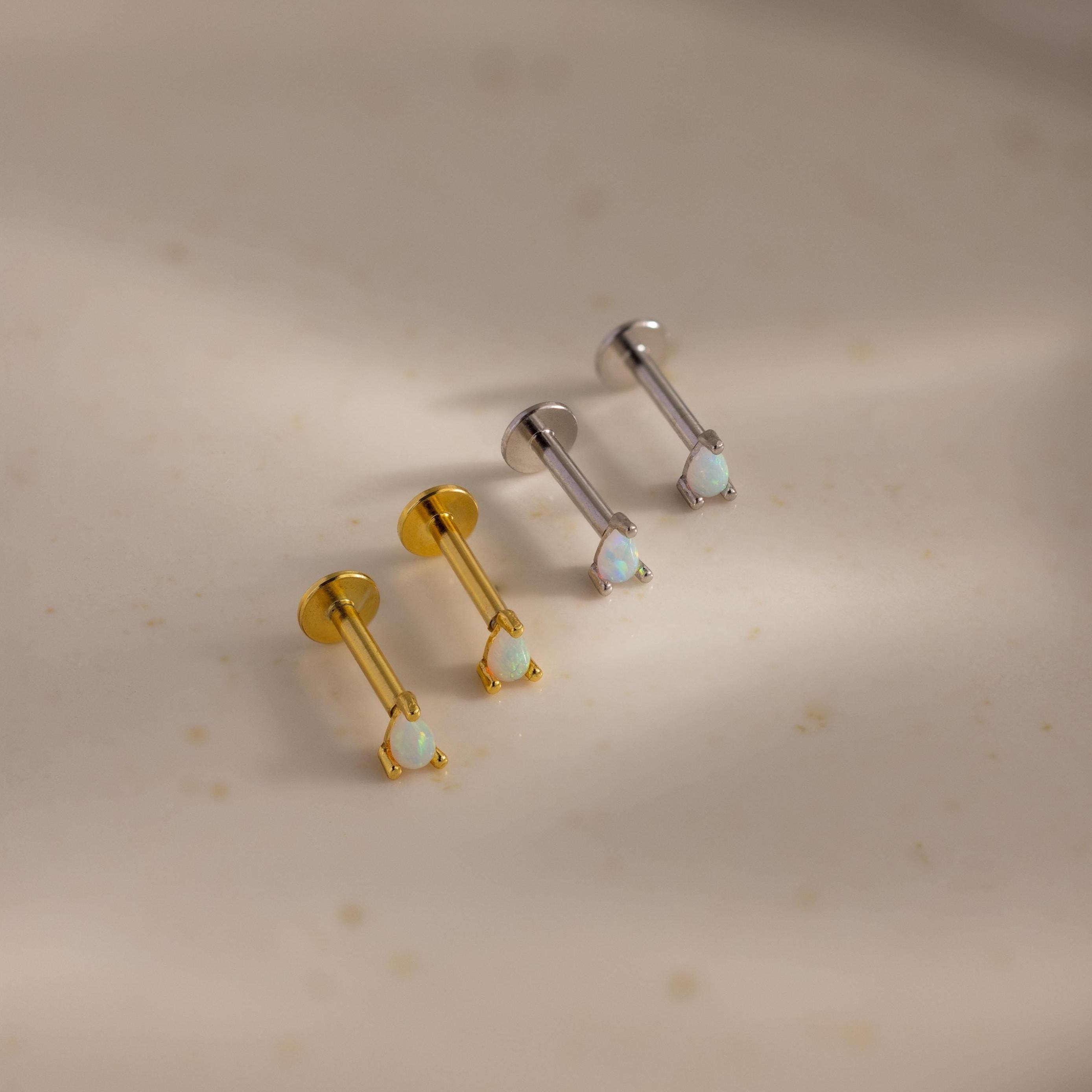 A symmetrical row of four pear opal flatback studs—two in gold and two in silver—displayed on a smooth, neutral background.
