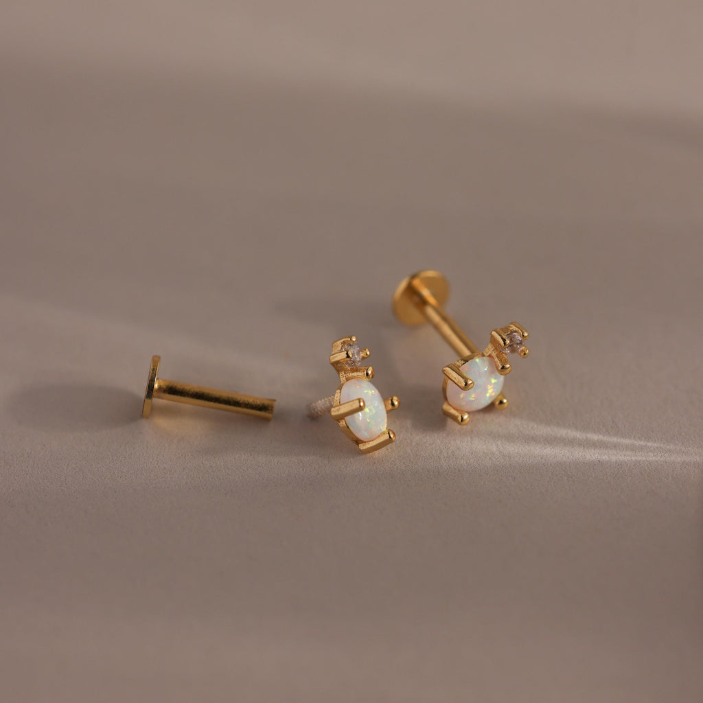 Gold opal and diamond flat back earrings laid out with visible backing mechanisms.