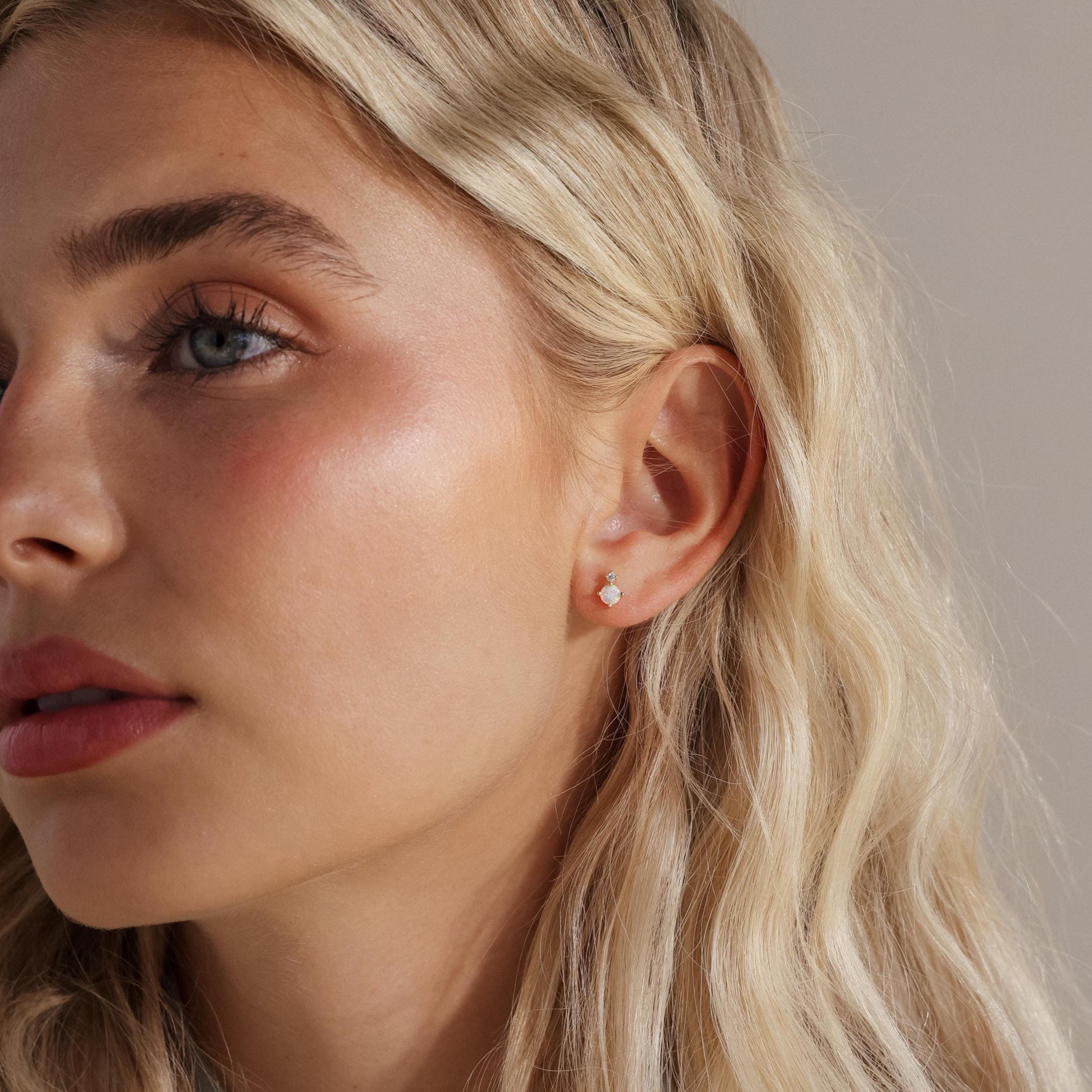 Model showing a side profile with a single silver opal and diamond earring visible.