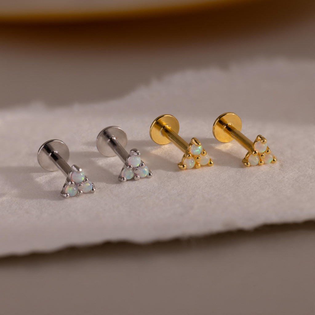 A lineup of four Opal Cluster Stud Earrings on a pale surface, showing two in silver and two in gold metal finish.