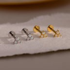 A lineup of four Opal Cluster Stud Earrings on a pale surface, showing two in silver and two in gold metal finish.