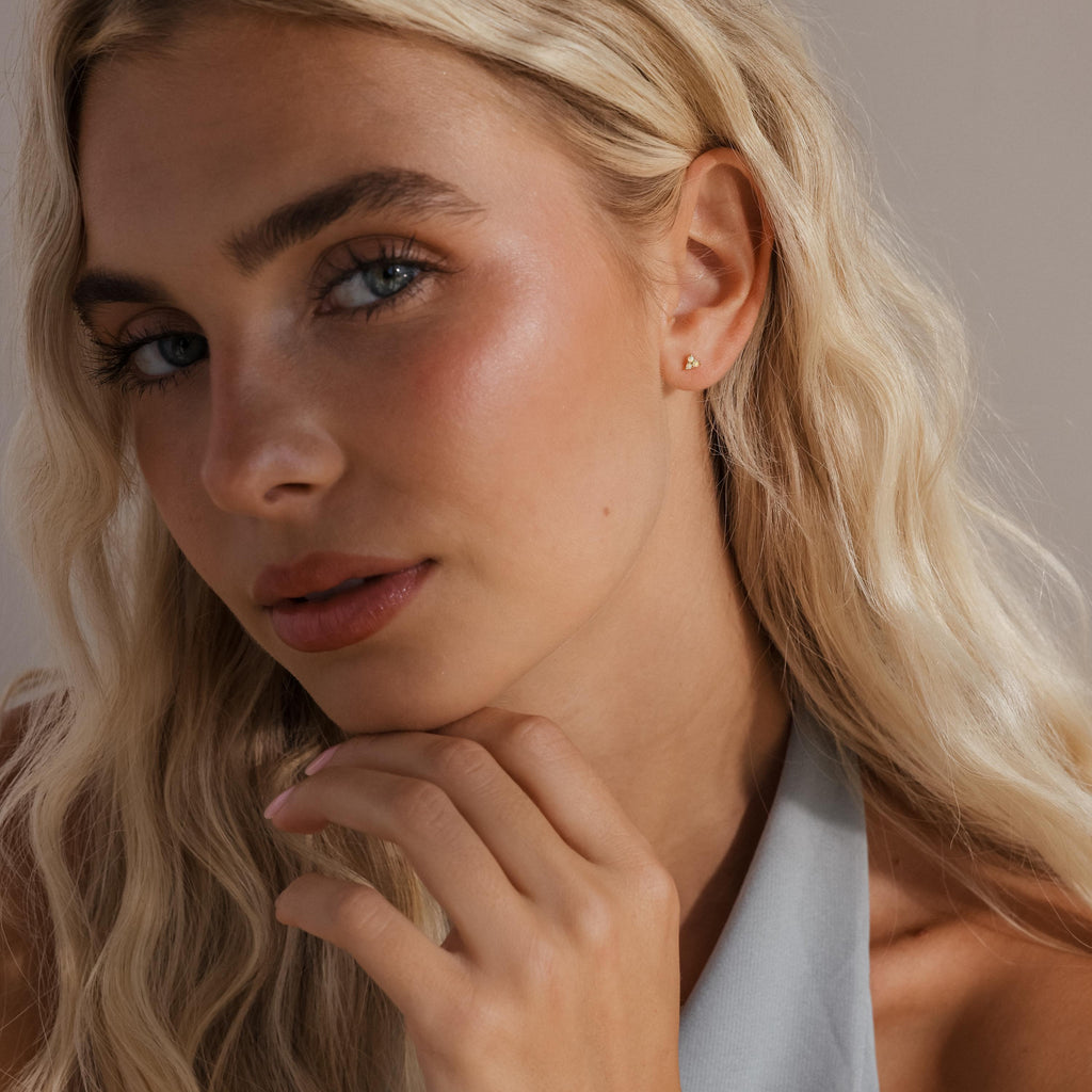 Model wearing a single opal cluster stud on her ear, with a soft, natural makeup look and styled blonde hair.