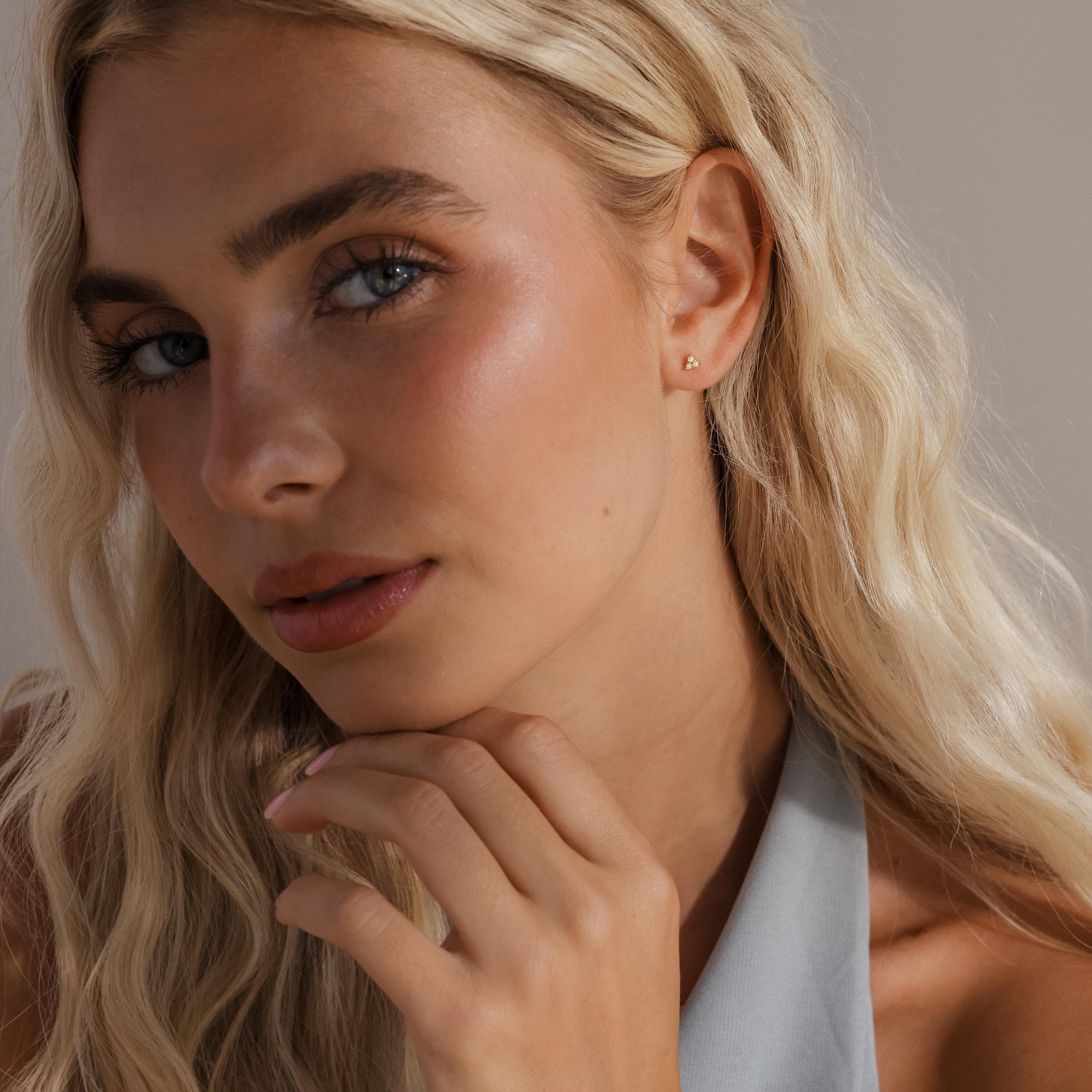 Model wearing a single opal cluster stud on her ear, with a soft, natural makeup look and styled blonde hair.