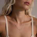 A woman wearing the silver Dainty Bow Necklace, which rests lightly along her collarbone.