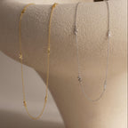 Gold and silver Dainty Bow Necklaces draped over a rounded jewelry display to showcase their delicate movement and design.