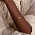 White gold version of the Heart Carabiner Paperclip Bracelet worn on wrist, styled with white blouse.