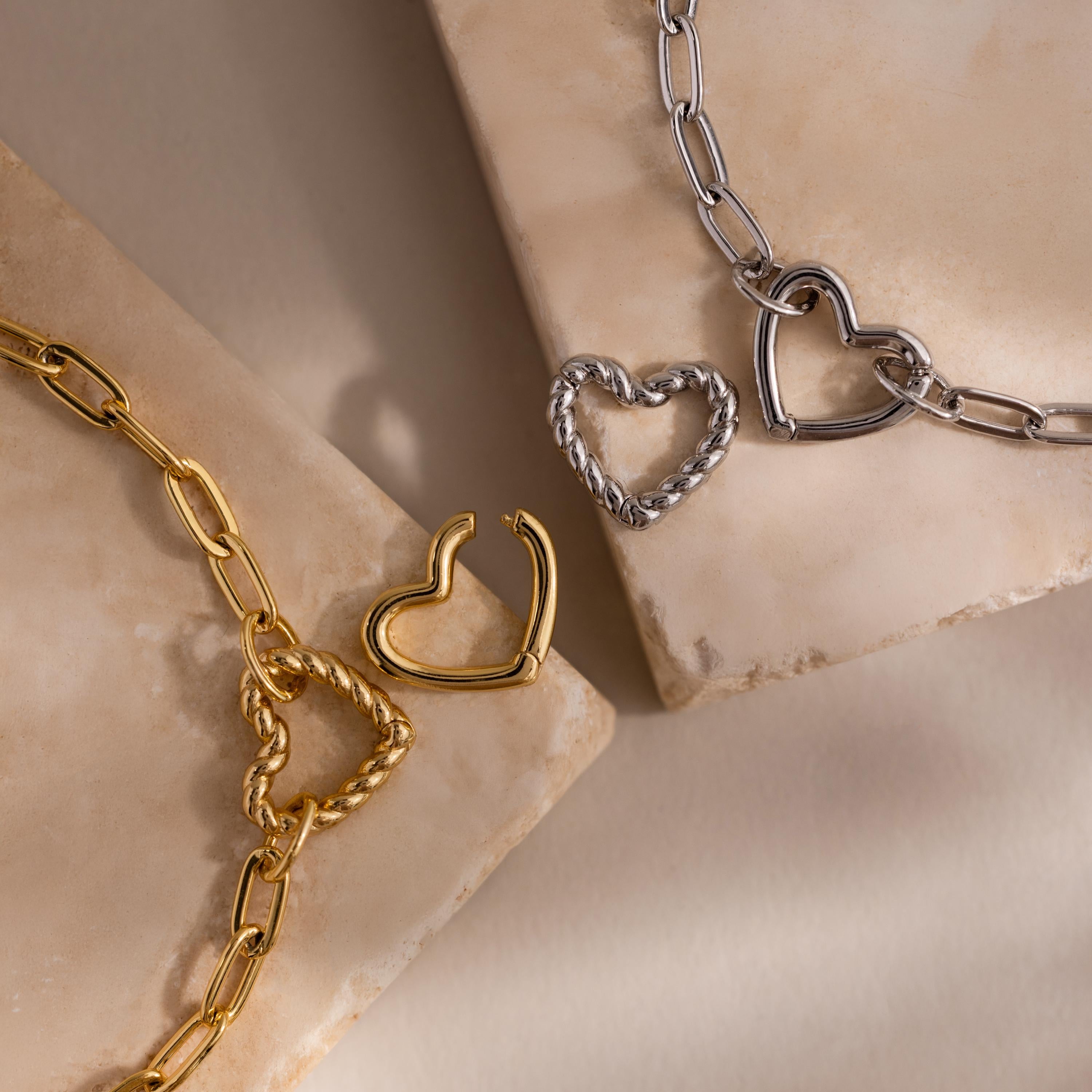 Close-up of both gold and white gold Heart Carabiner Paperclip Bracelets with interchangeable heart charms.
