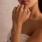 Woman wearing a delicate gold hand chain bracelet with bezel-set diamonds.