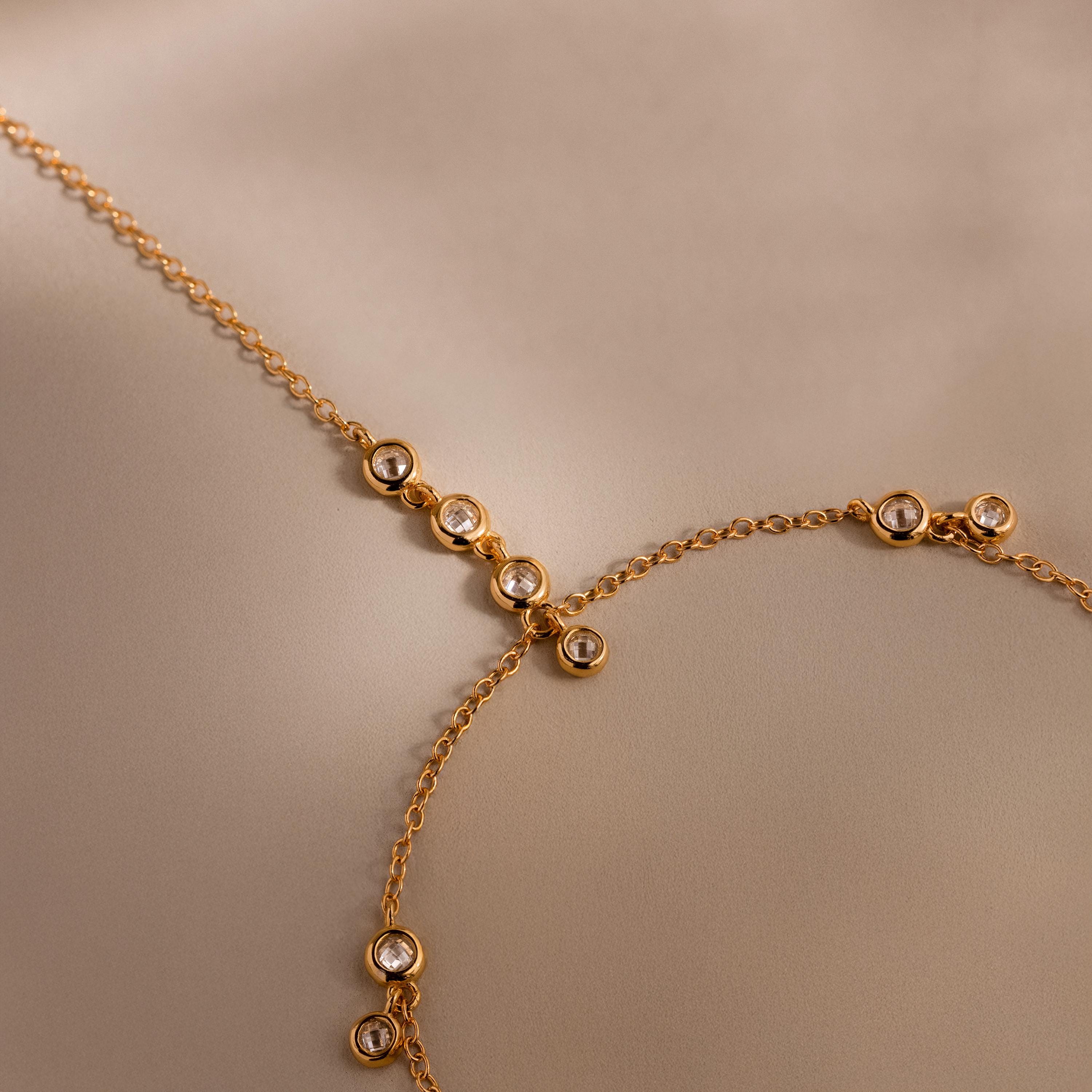 Macro shot of gold chain with bezel-set diamonds on a neutral background.