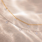 Gold and silver teardrop necklaces laid side-by-side with the light highlighting the shine of the stones
