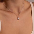A close-up shot of the white gold Puff Heart Pendant worn around the neck, resting at the collarbone.