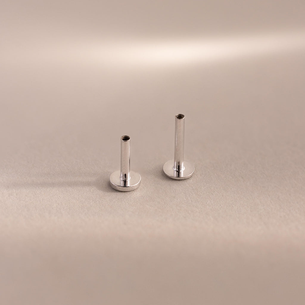 Two sterling silver Flat Back Posts standing upright side-by-side on a soft taupe backdrop.