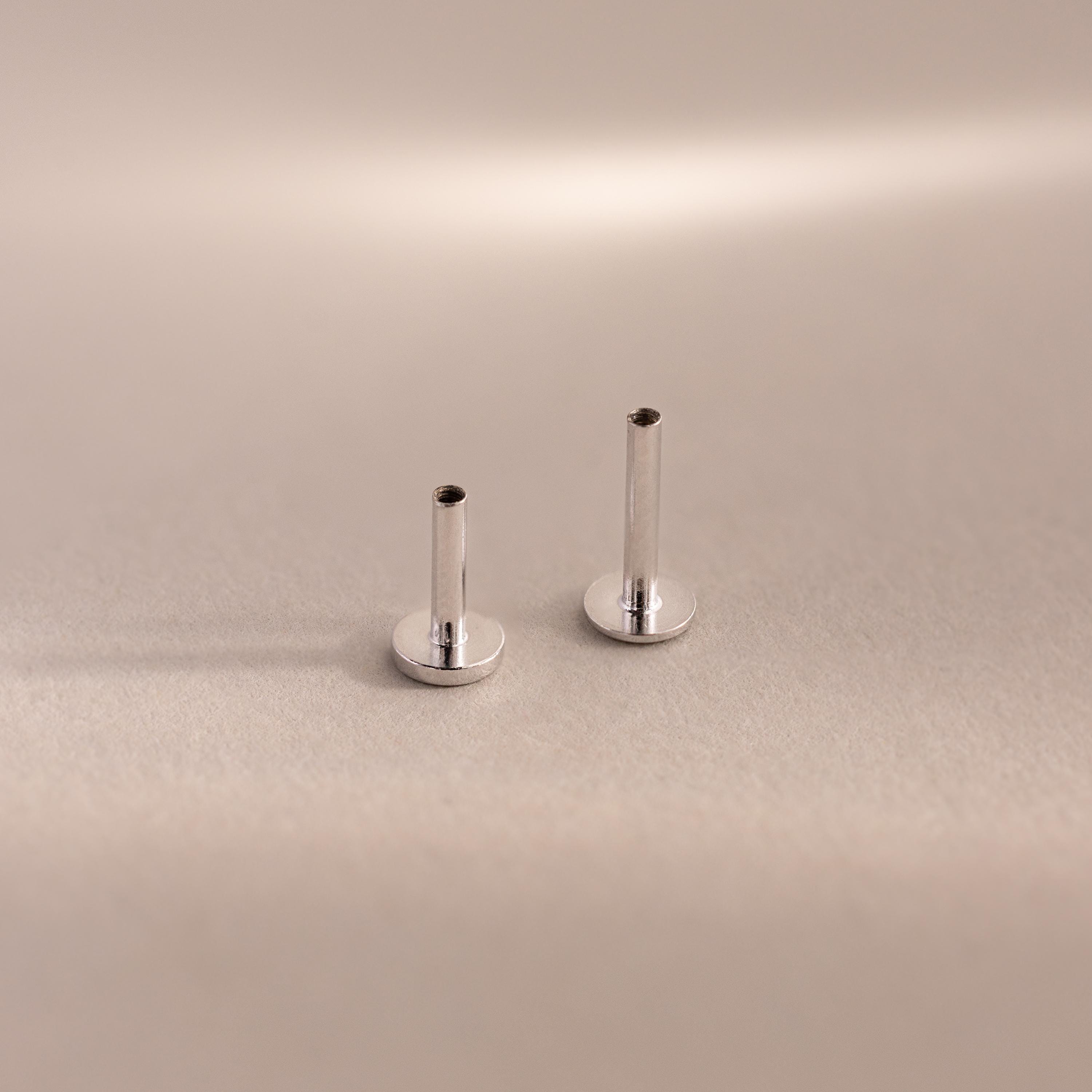 Two sterling silver Flat Back Posts standing upright side-by-side on a soft taupe backdrop.