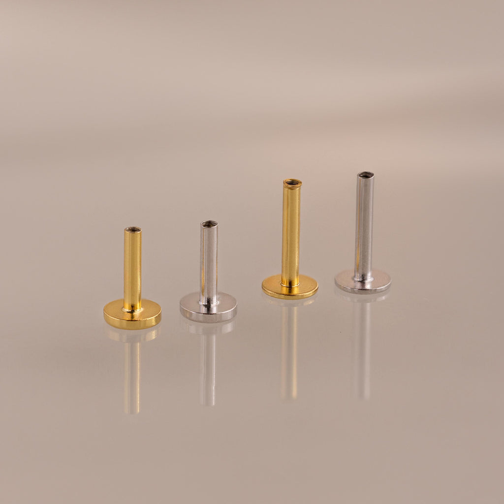 The Flatback Post Set features two gold and two silver posts arranged in a row on a reflective surface, highlighting their sleek design ideal for everyday ear jewelry.