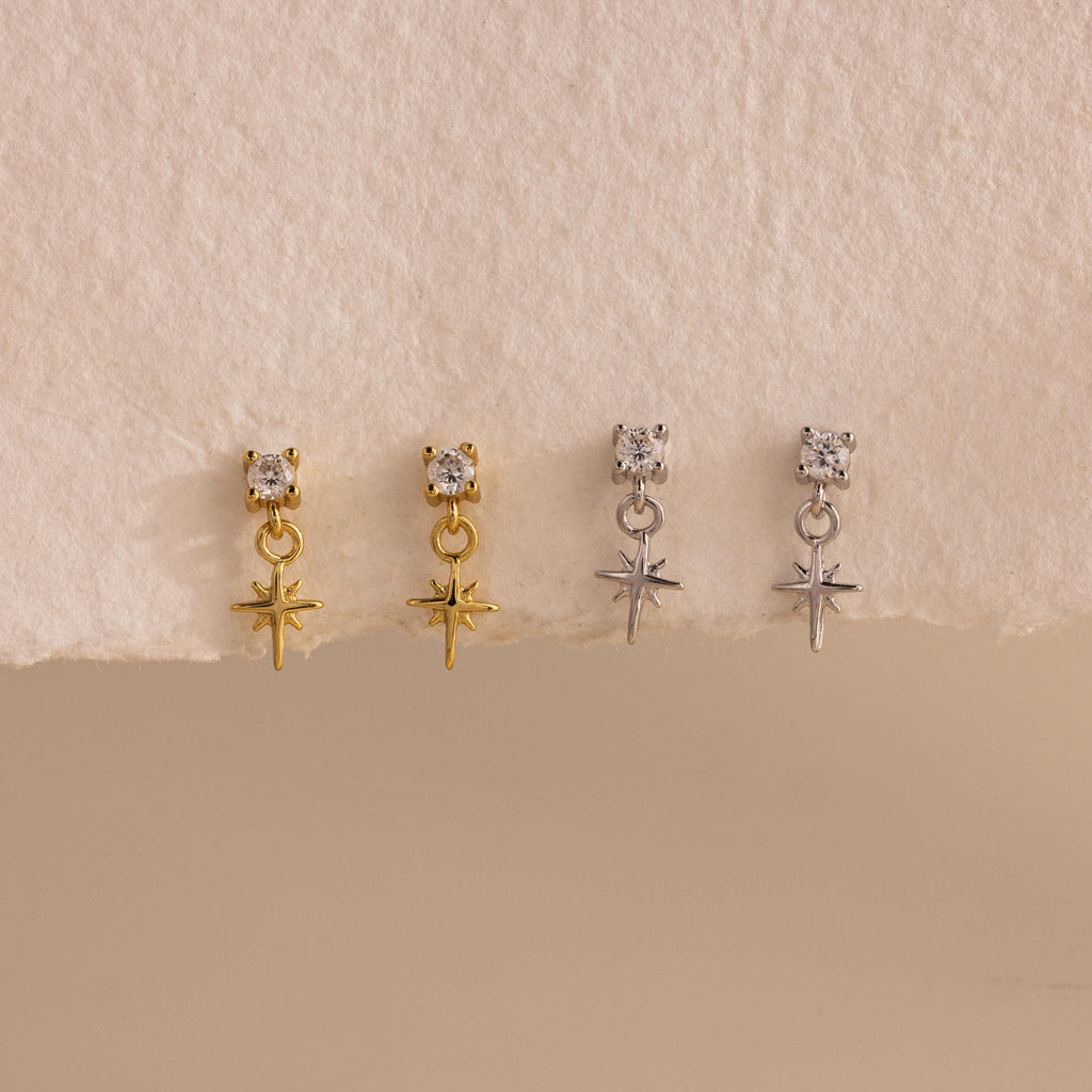 A side-by-side product display of all finish options: two pairs of 18k gold earrings and two pairs in sterling silver, lined up evenly on a softly textured white surface.
