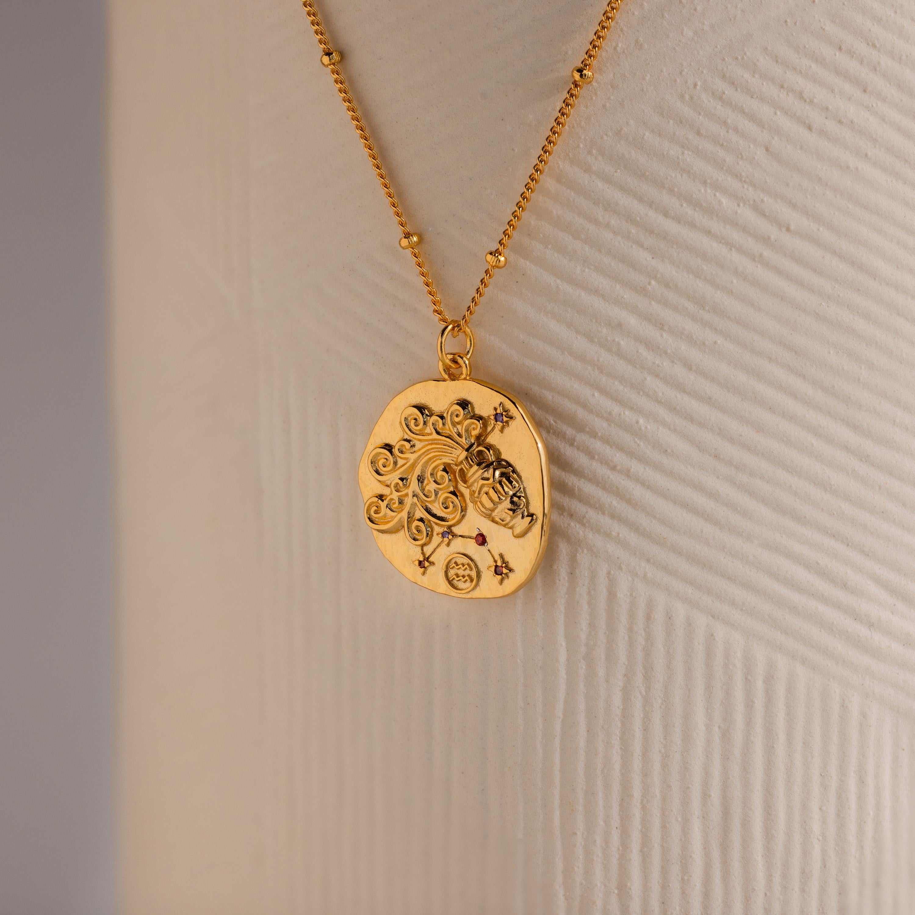 Close up of a Gold 3D Aquarius Zodiac Coin Pendant Necklace with small CZ gemstones, attached to a dainty satellite chain.