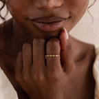 A woman gently resting her hand near her face, wearing a delicate marquise jade ring in a gold band that complements her natural makeup.