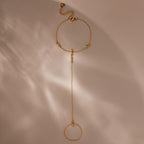 Flat-lay of a full gold hand chain bracelet with extension clasp, photographed on soft beige.