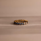 Gold eternity band set with marquise cut stones in a gradient of deep navy to soft icy blue, arranged in an ombré effect. Each stone is held by delicate prongs, creating a continuous shimmer around the ring.