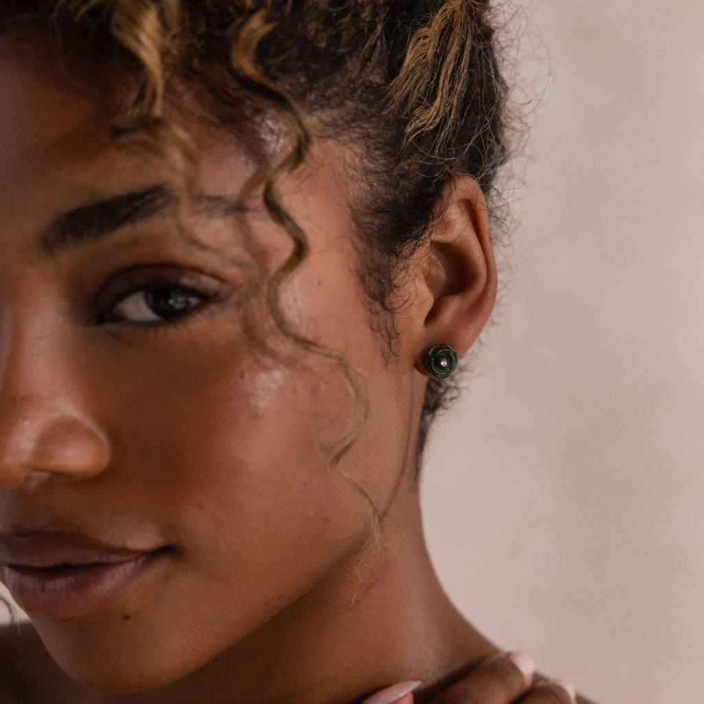 Portrait of a woman wearing a green jade rose stud earring, styled with minimal makeup and soft curls.