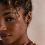 Portrait of a woman wearing a green jade rose stud earring, styled with minimal makeup and soft curls.