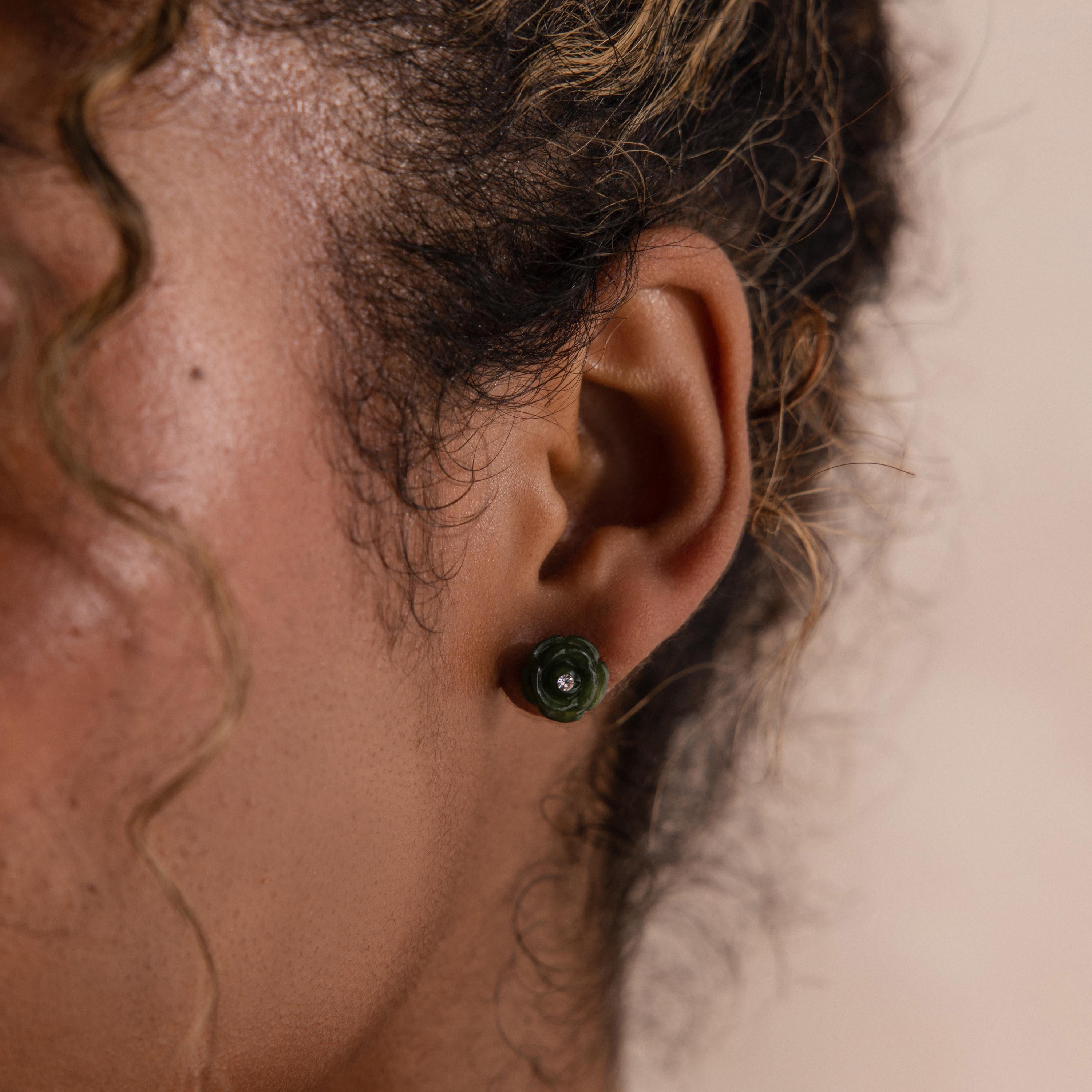 Close up of a woman wearing a green jade rose stud earring, styled with soft curls.