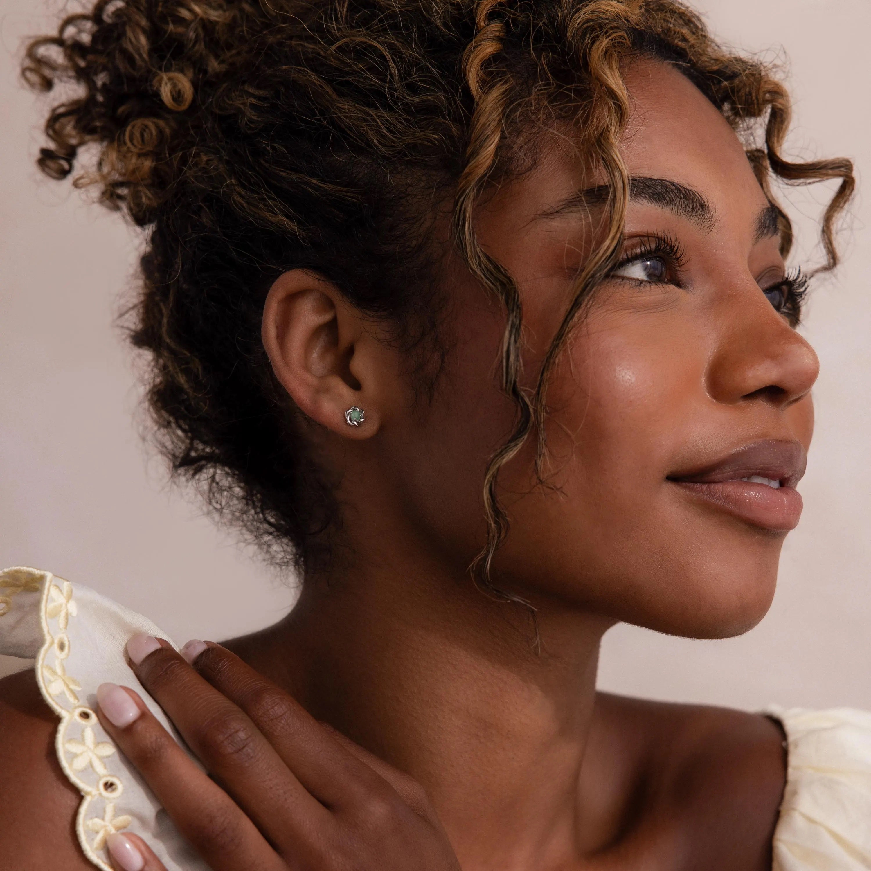 Model wearing a silver flower-shaped stud earring with a round green jade gemstone center.