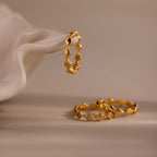 Set of 3 eternity curve rings in gold, featuring quilted design with one diamond-accented band, elegantly displayed on soft neutral fabric.