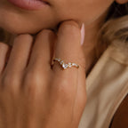 Gold heart curve cluster diamond ring with heart shaped and round diamonds shown on a woman's hand.