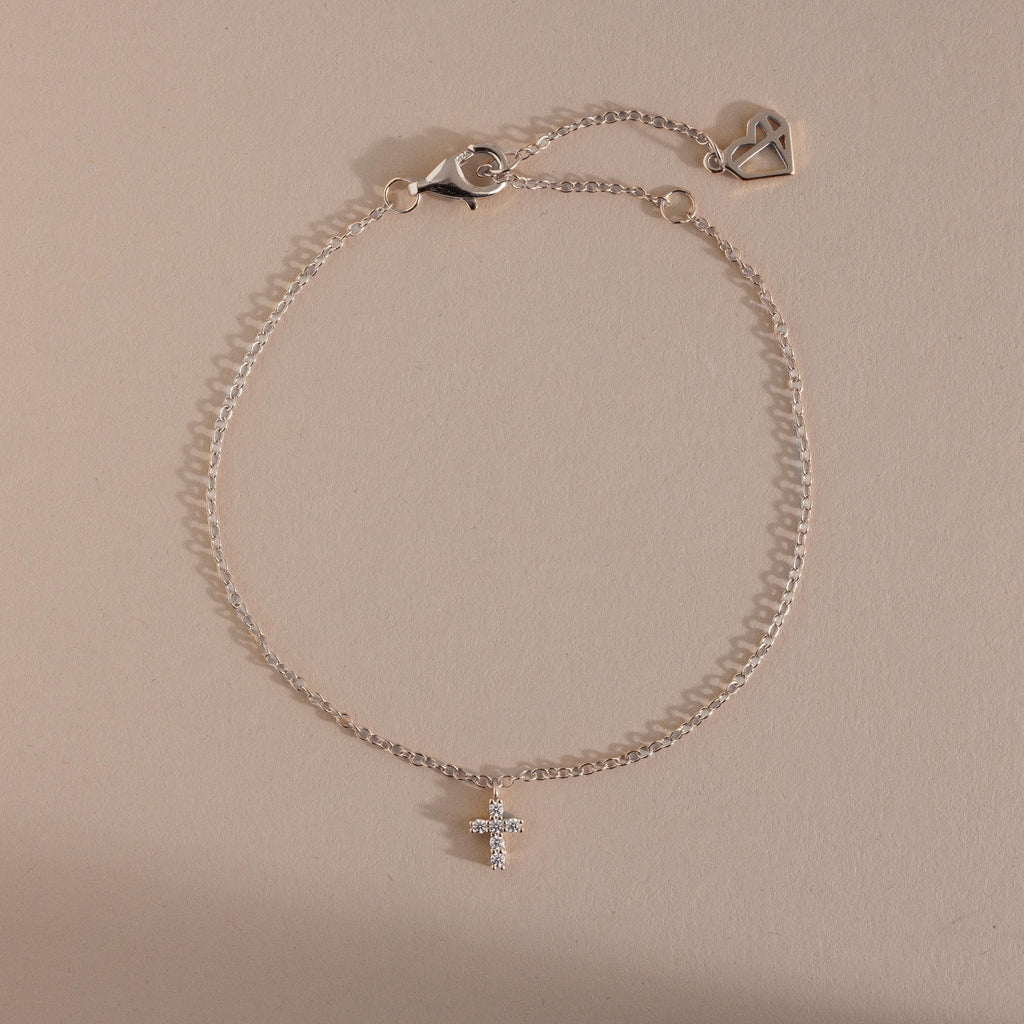 Silver chain bracelet with a sparkling crystal cross charm and adjustable clasp featuring a heart detail, a timeless and elegant accessory perfect for layering or everyday wear.