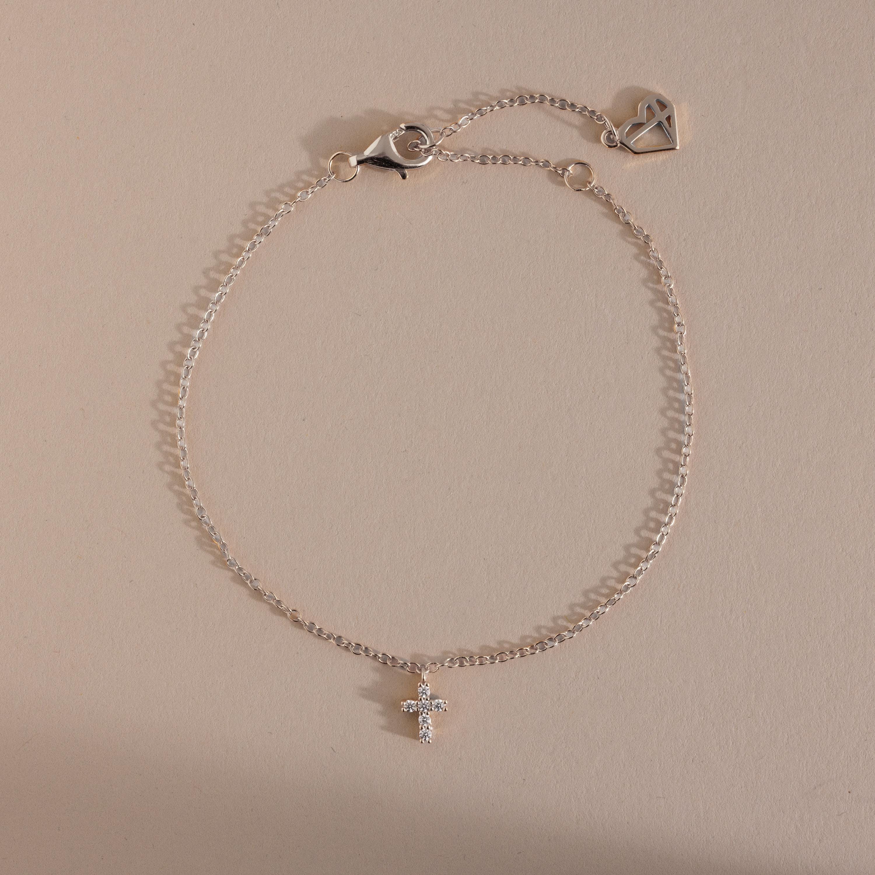Silver chain bracelet with a sparkling crystal cross charm and adjustable clasp featuring a heart detail, a timeless and elegant accessory perfect for layering or everyday wear.