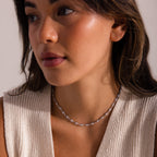 Woman wearing a silver pearl chain necklace, featuring small white pearls evenly spaced along delicate metal links.