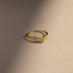 Minimal gold ring with a curved row of baguette and marquise cut clear stones, shown in soft natural light against a neutral background for a modern, elegant presentation.