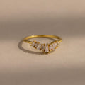 Delicate gold ring with a row of tapered baguette and marquise cut clear gemstones set in a subtle curved design, creating a refined and elegant look.