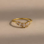 Delicate gold ring with a row of tapered baguette and marquise cut clear gemstones set in a subtle curved design, creating a refined and elegant look.