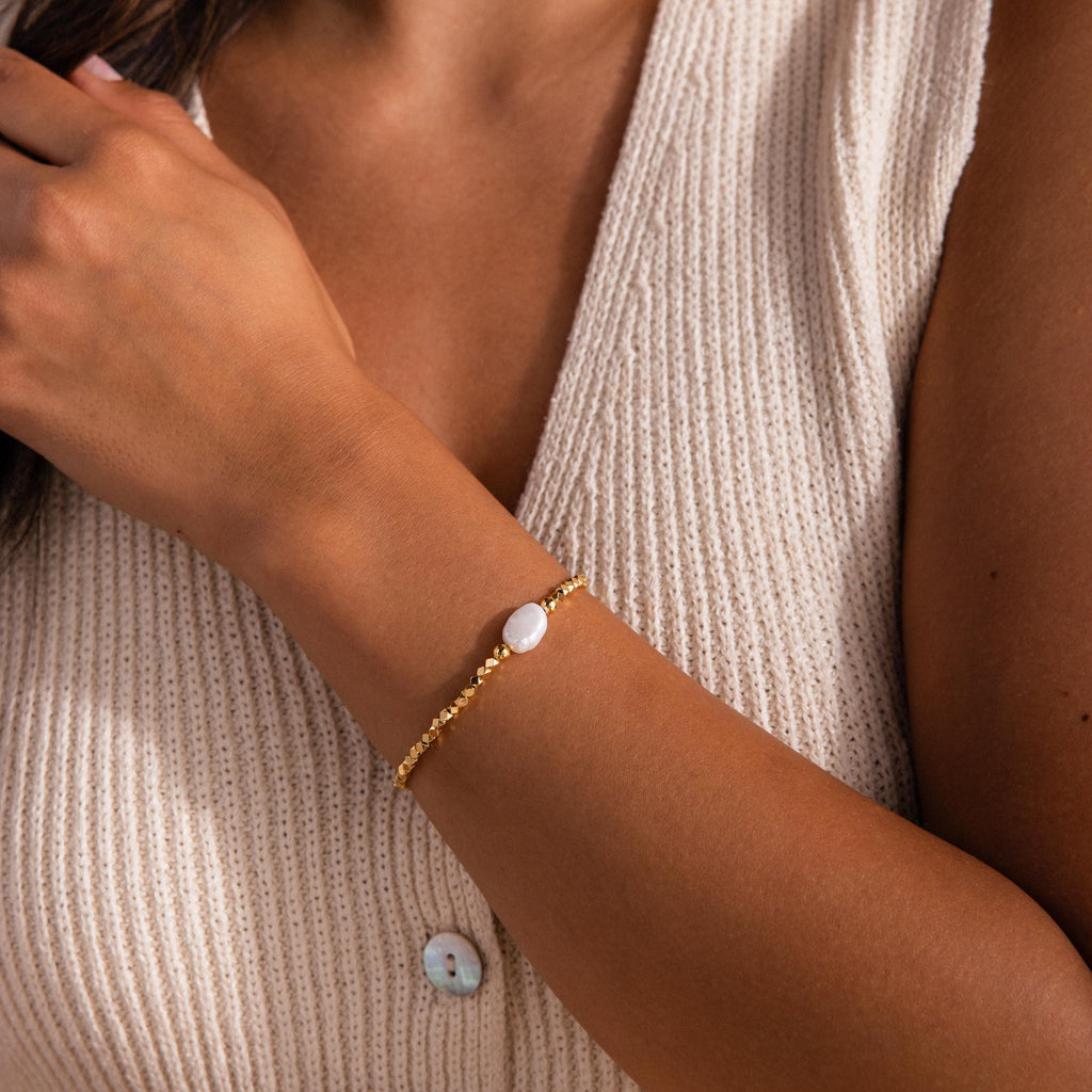 Beaded Pearl Bracelet featuring small faceted gold beads with a single natural white pearl centerpiece, styled on the wrist for a delicate and elegant look.