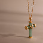 Gold chain necklace with a jade cross pendant, accented by polished gold end caps and an X shaped detail at the center.