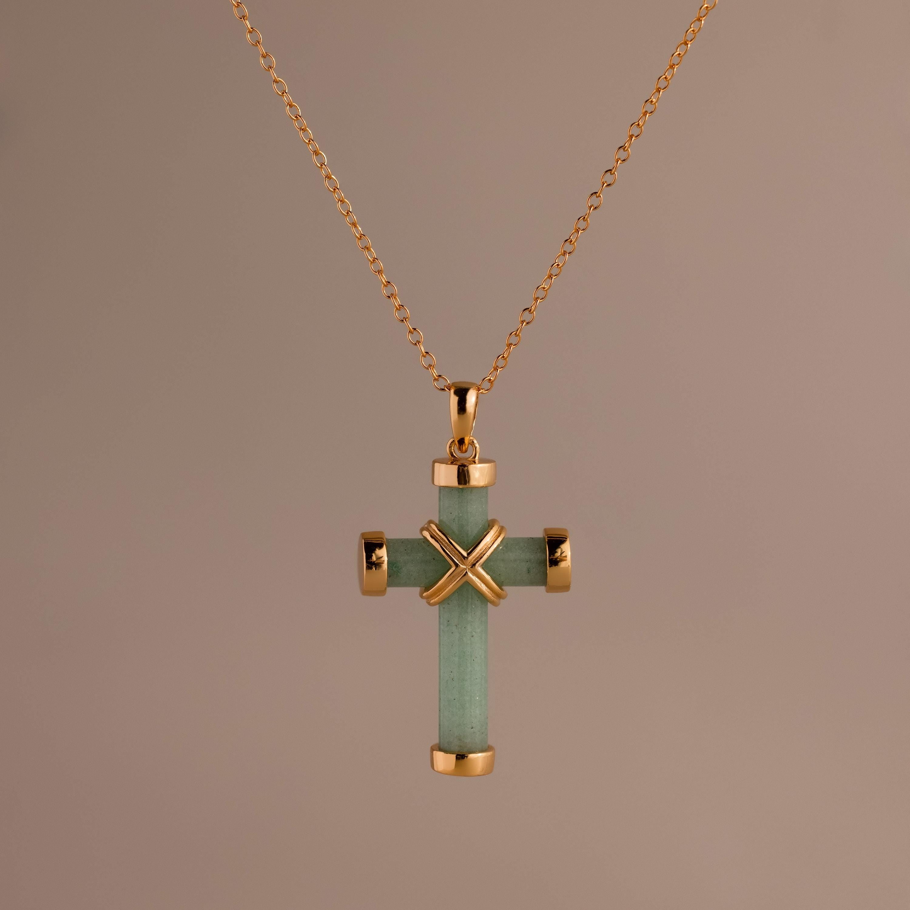 Gold chain necklace featuring a green jade cross pendant with polished gold end caps and a gold X-shaped accent at the center.