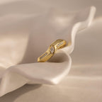 Radiant Facet Ring in polished gold featuring a diamond shaped CZ stone center with pave side stones, displayed on sculpted ivory fabric.