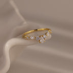 Radiant Tear Ring in polished gold featuring a pear-cut diamond center with marquise and round side stones, displayed on draped ivory fabric.