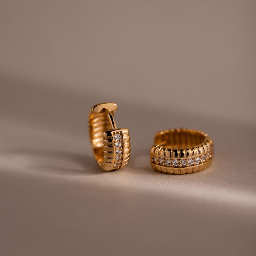 Two Ribbed Pave Huggies featuring sparkling diamonds make a striking statement, displayed on a neutral background.